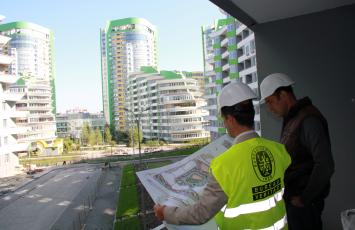 Bureau Veritas employee viewing building plans with someone as they stand outside in front buildings