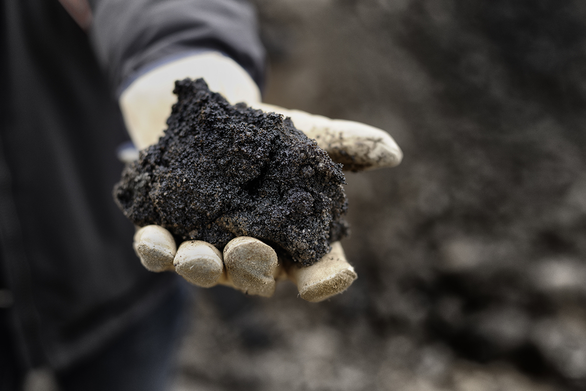 Gloved hand holding soil with hydrocarbons