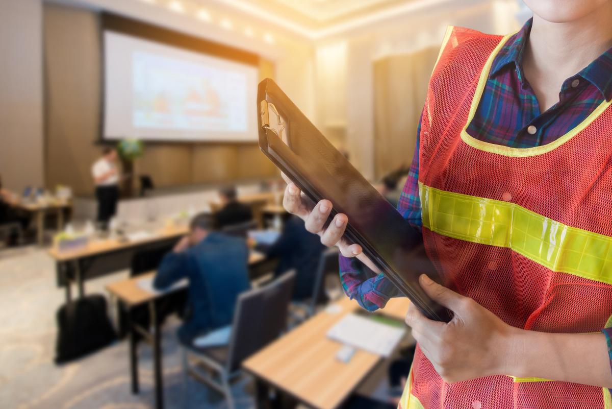 Woman wearing safety vest holding clipboard in training room