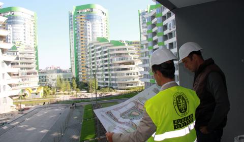Bureau Veritas employee viewing building plans with someone as they stand outside in front buildings