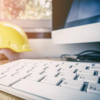 Yellow hardhat by computer keyboard
