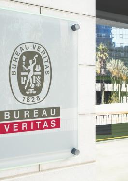 The front of a white building with a BV logo by the front door