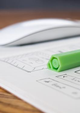 Open notebook with a green highlighter on the right side and a computer mouse on the left