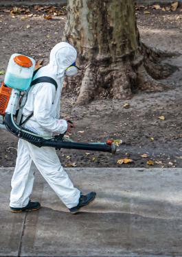 Person in hazmat suit sanitizing street