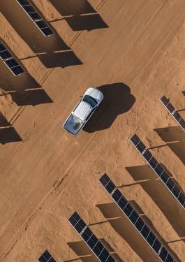 White pickup truck driving through a plot of solar panels 