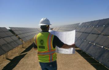 Bureau Veritas employee looking at plans out in a solar panel field