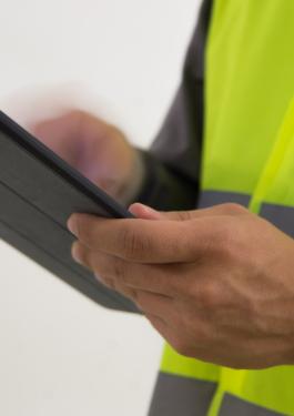 Employee in PPE vest, holding a tablet
